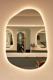Modern vanity with a large oval mirror featuring embedded lighting.