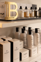 Balmain hair care products on a shelf with a large gold letter 'B'.