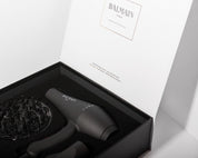 Black hair dryer with accessories in a Balmain branded box on a white background