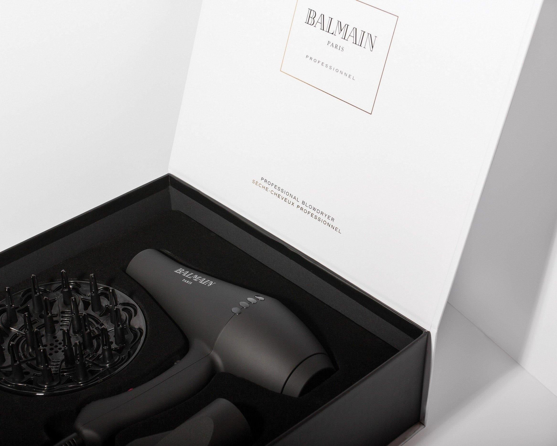 Black hair dryer with accessories in a Balmain branded box on a white background