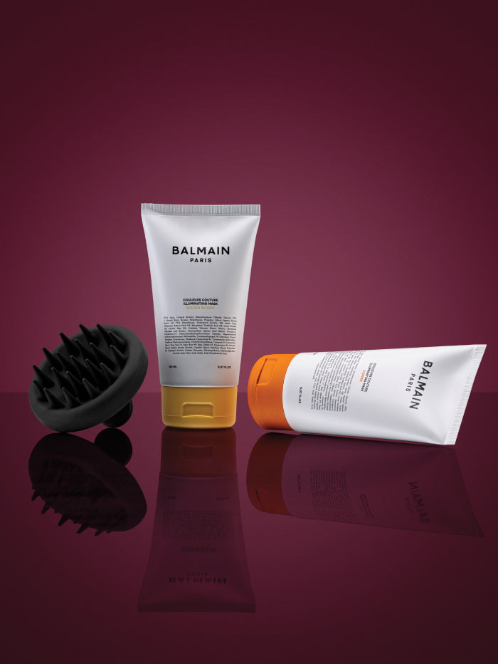 Balmain hair care products on a reflective surface with a purple background