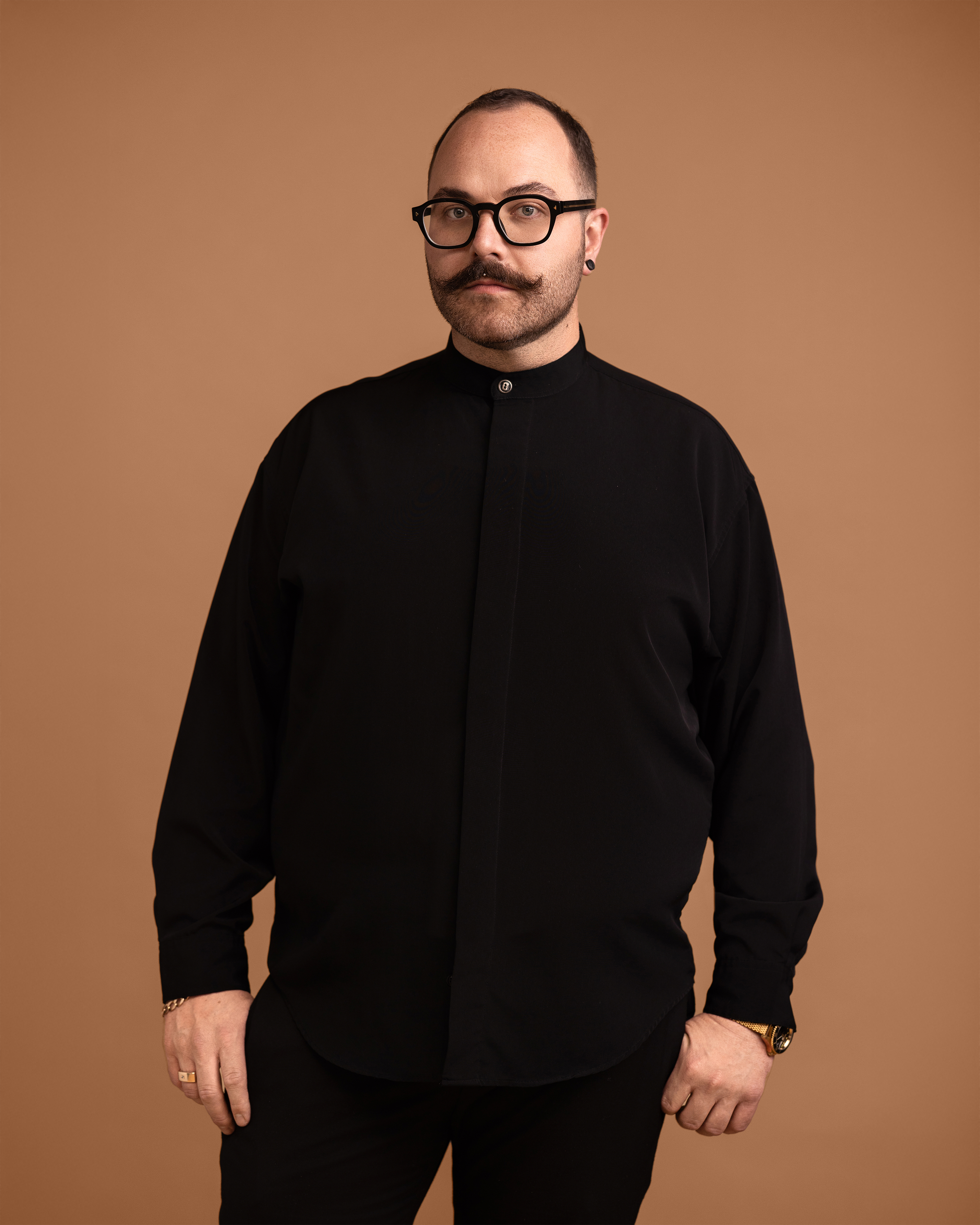 Man wearing a black outfit against a brown background