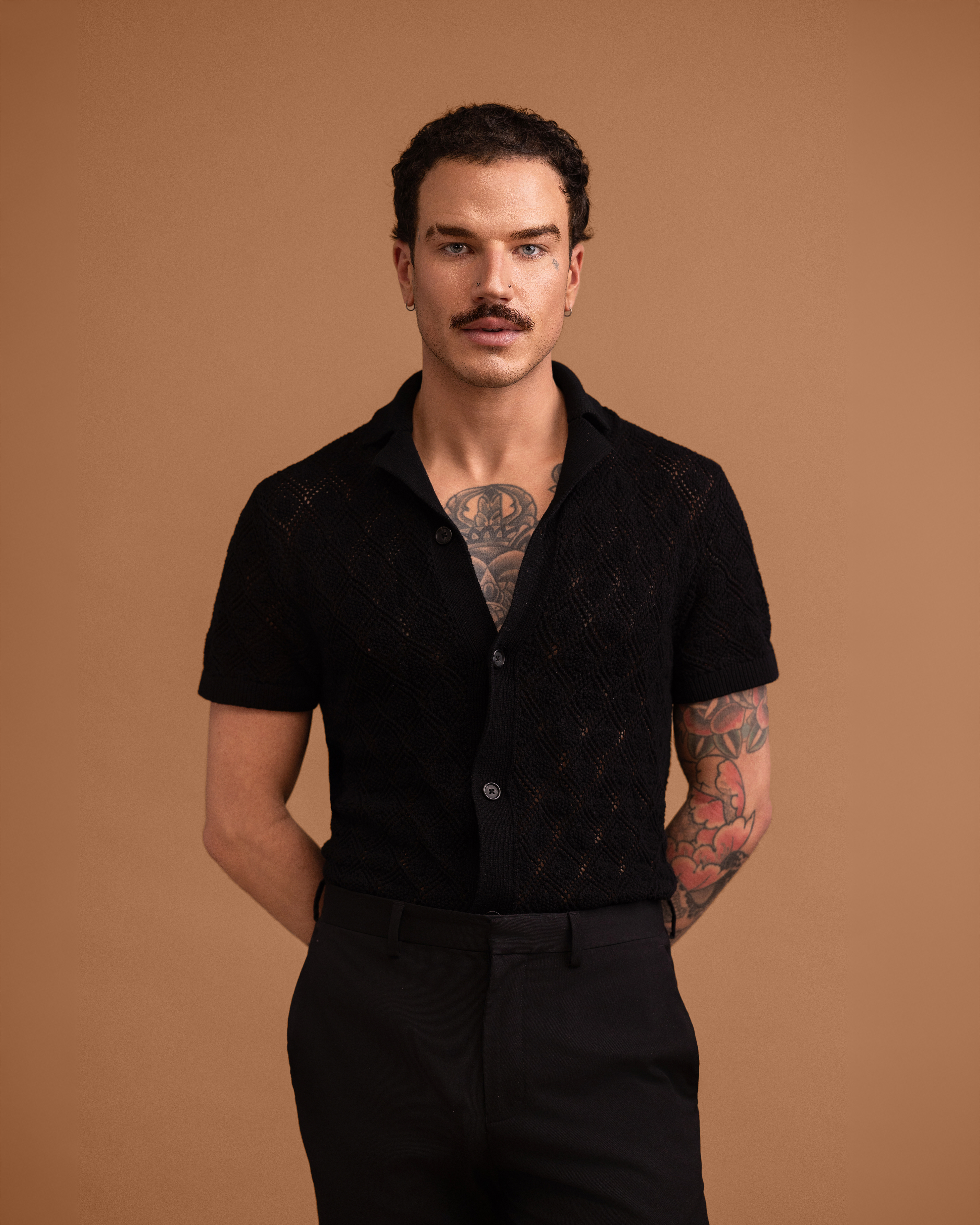 Man wearing a black shirt and pants against a brown background