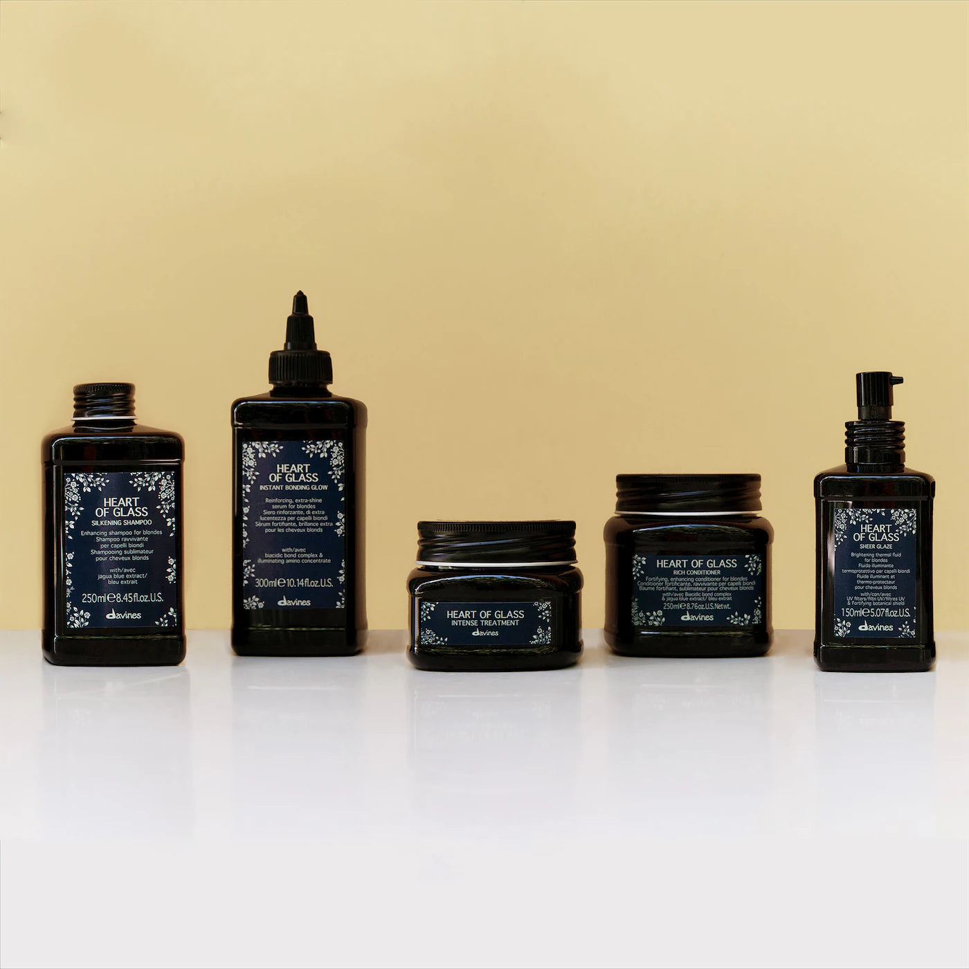 Set of haircare products with 'Heart of Glass' branding on a beige background