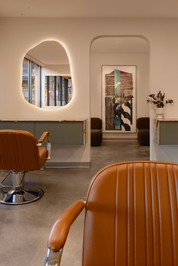 Modern interior with brown leather chairs and a round mirror.