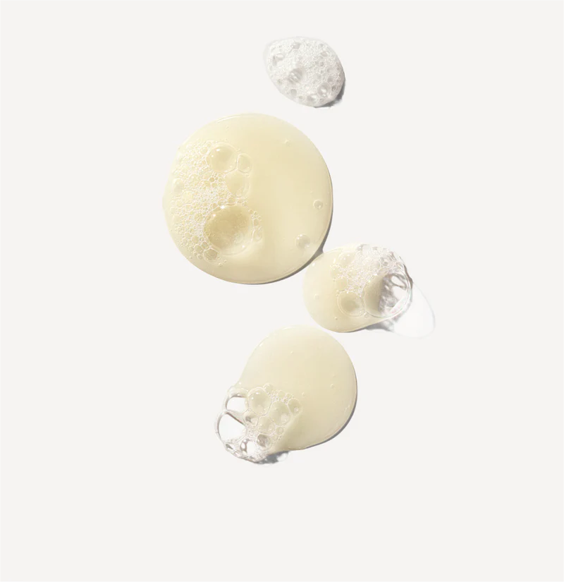 Three droplets of shampoo on a light gray background