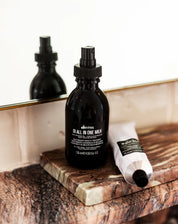 Black bottles and a tube of Davines hair care products on a marble surface.