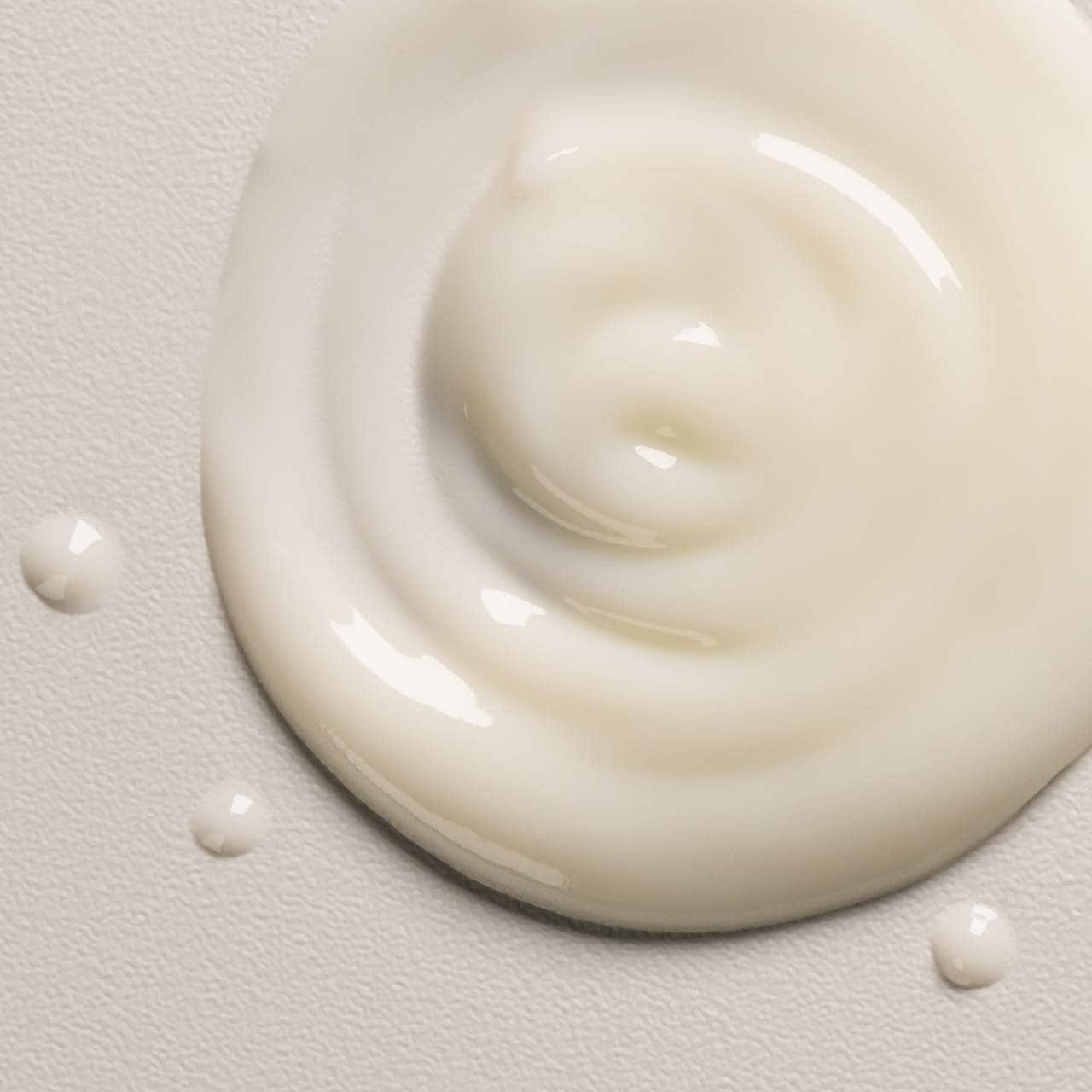 Close-up of a swirl of white cream on a light gray background