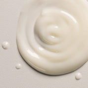 Close-up of a swirl of white cream on a light gray background