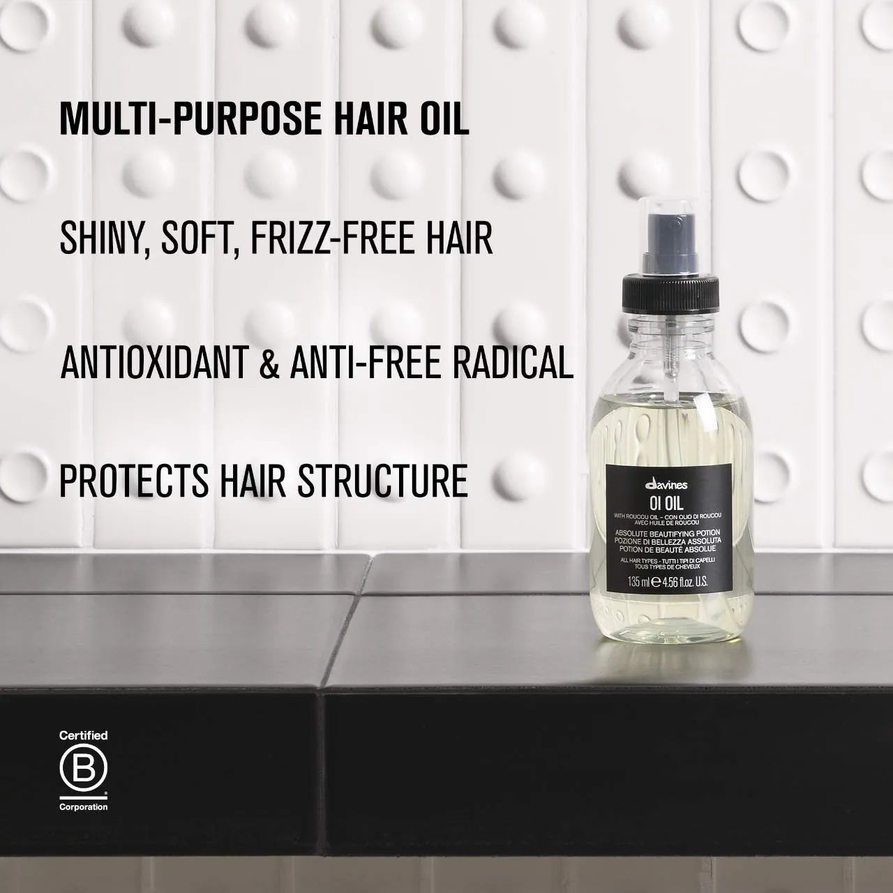 Bottle of hair oil on a gray surface with text about hair care benefits.