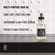 Bottle of hair oil on a gray surface with text about hair care benefits.
