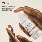 Olaplex hair treatment product with hands holding it on a light background