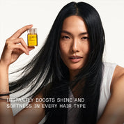 Woman holding a bottle of hair oil with text about its benefits