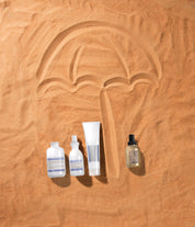 haircare products on a sand background with an umbrella design