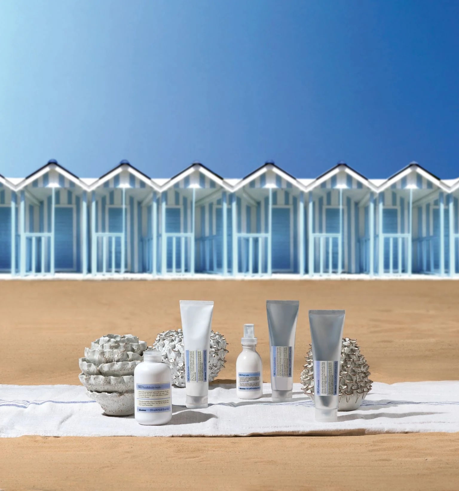 davines products on a wooden surface with beach huts and blue sky in the background