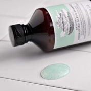 Bottle of natural scrub with a sample on a white surface