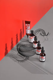 products including bottles and a tube on a gray surface with a red background