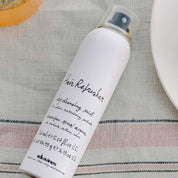 White spray bottle labeled 'Hair Refresher' on a textured surface