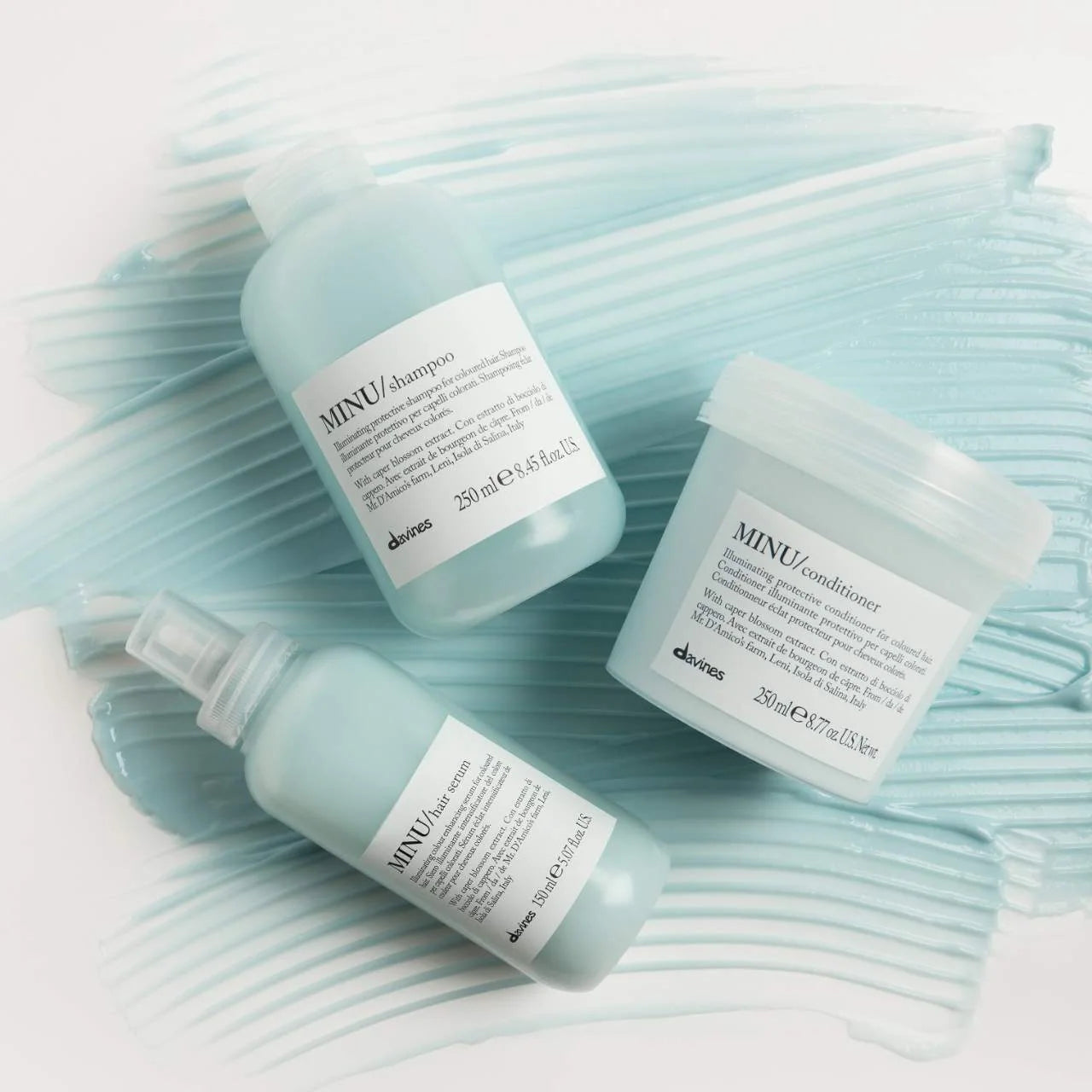 Davines hair care products including shampoo, conditioner, and hair mist on a textured light blue background.