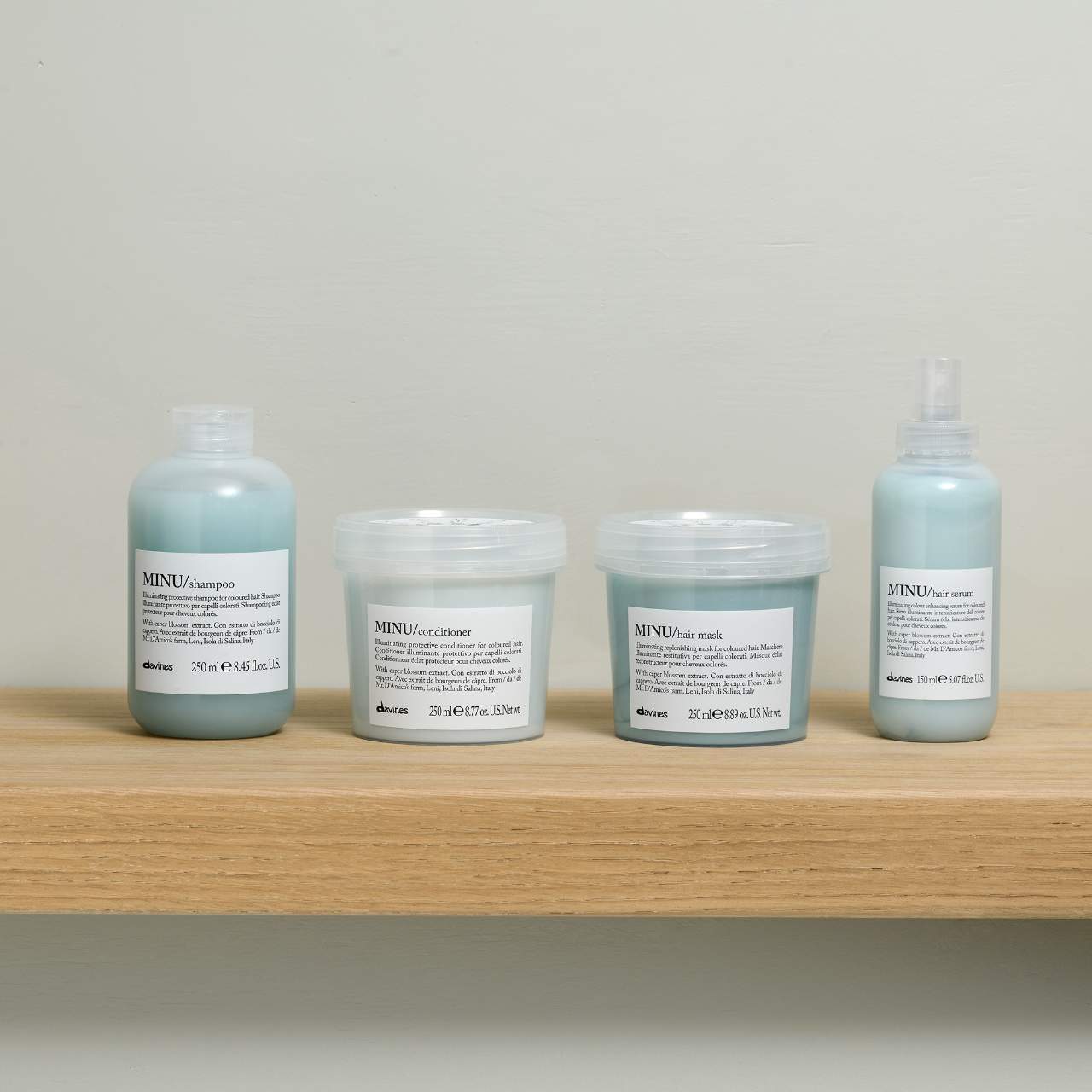 Set of Davines hair care products on a wooden shelf with a neutral background