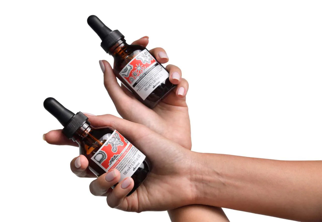 Two bottles of a product held in hands against a white background