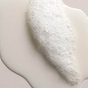 Close-up of a white, creamy product foam on a light gray background